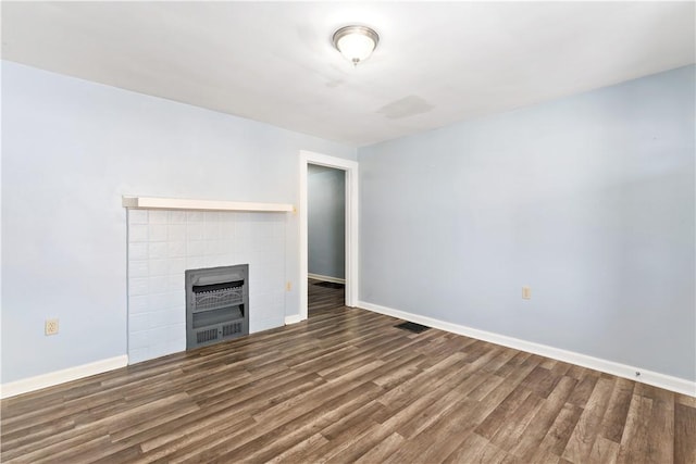 unfurnished living room featuring visible vents, a tiled fireplace, baseboards, and wood finished floors