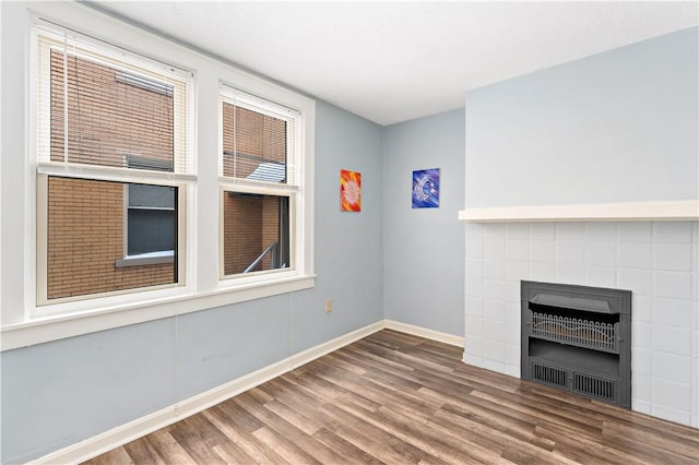 unfurnished living room featuring heating unit, a fireplace, baseboards, and wood finished floors