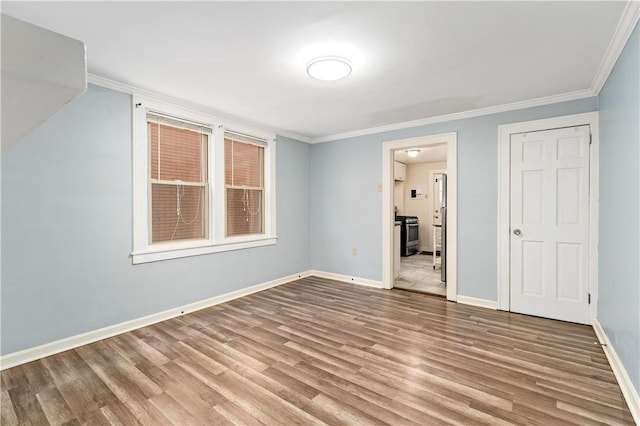 unfurnished room with ornamental molding, baseboards, and wood finished floors