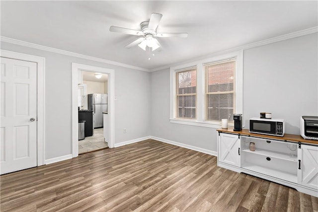 unfurnished office with light wood-style floors, ornamental molding, baseboards, and ceiling fan