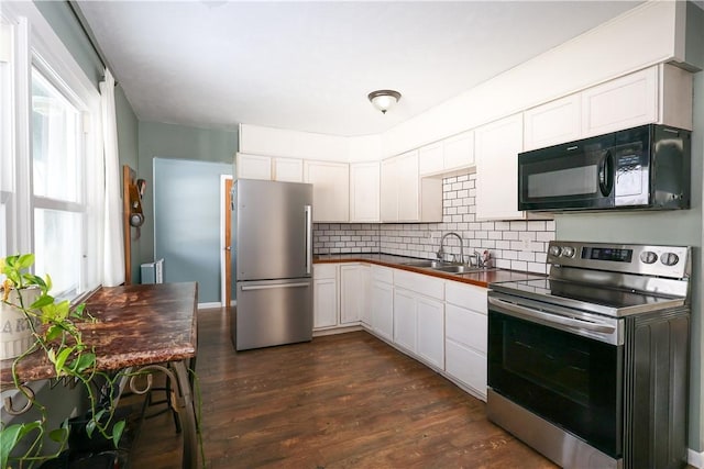 kitchen featuring tasteful backsplash, dark wood finished floors, dark countertops, appliances with stainless steel finishes, and a sink