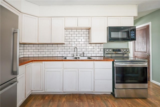 kitchen with appliances with stainless steel finishes, dark wood-type flooring, a sink, and backsplash