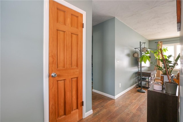 corridor featuring dark wood finished floors and baseboards