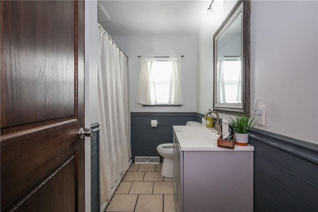 bathroom with tile patterned flooring, toilet, wooden walls, a wainscoted wall, and vanity