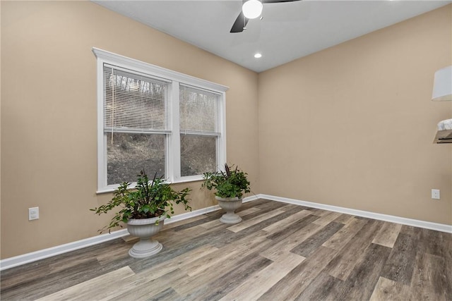 empty room with wood finished floors, a ceiling fan, and baseboards