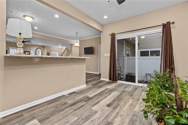 interior space featuring baseboards, ceiling fan, wood finished floors, crown molding, and recessed lighting