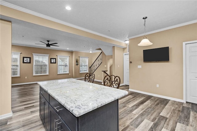 kitchen featuring baseboards, ceiling fan, ornamental molding, hanging light fixtures, and light wood-style floors