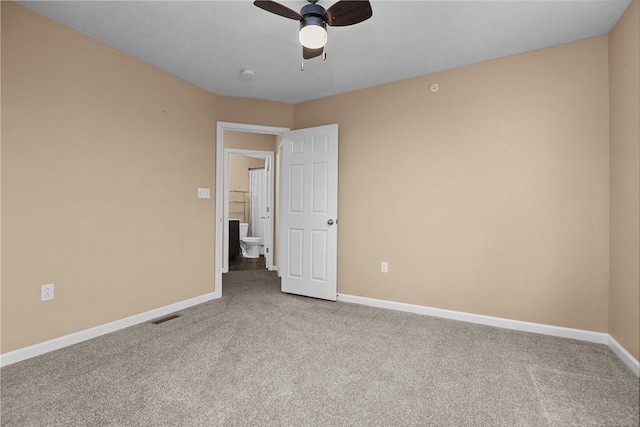 empty room featuring a ceiling fan, visible vents, baseboards, and carpet flooring