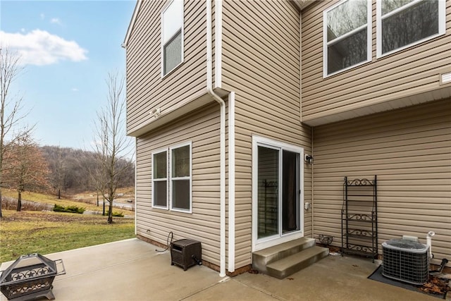 view of property exterior featuring entry steps, a patio, a fire pit, central AC, and a lawn