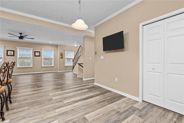 unfurnished living room with ornamental molding, stairway, baseboards, and wood finished floors