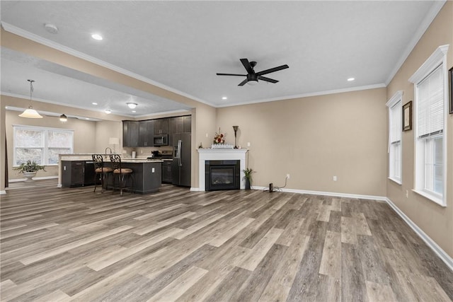 unfurnished living room featuring light wood-type flooring, a glass covered fireplace, crown molding, and baseboards