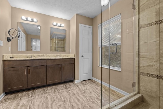 bathroom featuring double vanity, a shower stall, a sink, and a textured ceiling