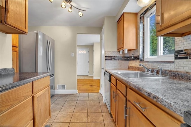 kitchen featuring appliances with stainless steel finishes, a sink, decorative backsplash, and light tile patterned floors