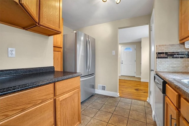 kitchen with light tile patterned floors, stainless steel appliances, visible vents, backsplash, and baseboards