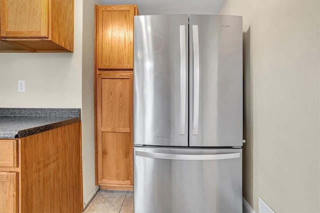 kitchen with dark countertops, light tile patterned floors, and freestanding refrigerator