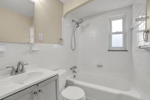 full bath featuring shower / bath combination, wainscoting, toilet, vanity, and tile walls