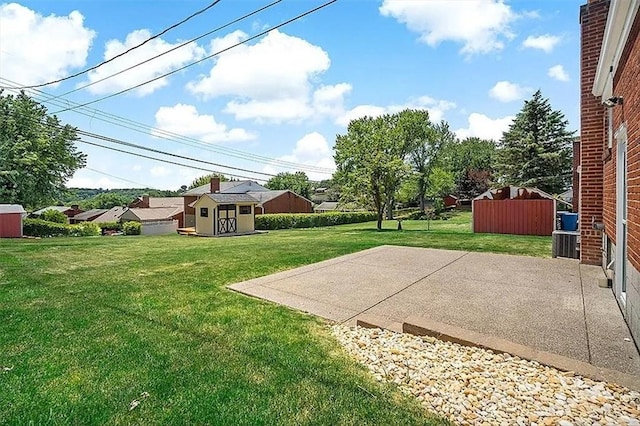 view of yard with central air condition unit, a shed, a patio, and an outbuilding