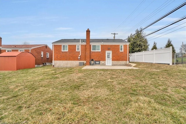 rear view of house with a patio, brick siding, fence, a yard, and a chimney