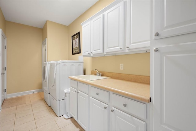 washroom featuring cabinet space, light tile patterned floors, baseboards, separate washer and dryer, and a sink