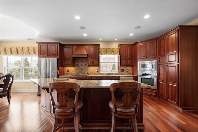 kitchen featuring stainless steel appliances, tasteful backsplash, custom range hood, and dark wood-style floors