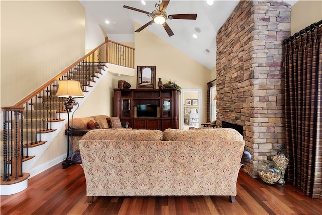 living room with high vaulted ceiling, stairway, dark wood finished floors, and a stone fireplace