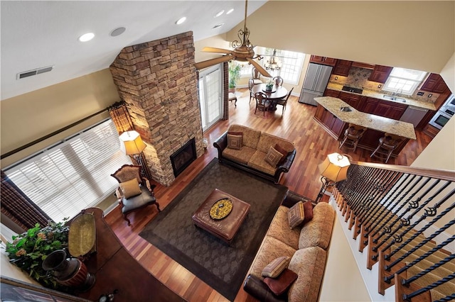 living area with high vaulted ceiling, a fireplace, wood finished floors, and visible vents