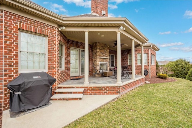 exterior space with a ceiling fan, brick siding, a yard, and a chimney