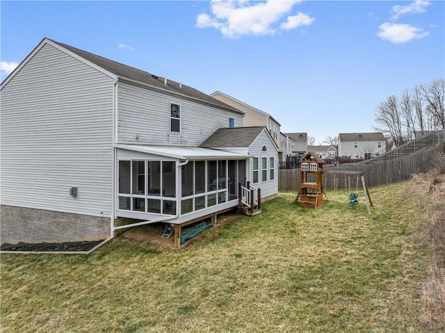 rear view of property featuring a sunroom, a playground, a yard, and fence