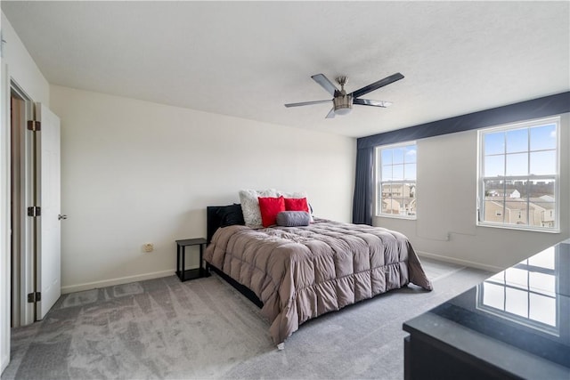 bedroom with ceiling fan, baseboards, and light colored carpet