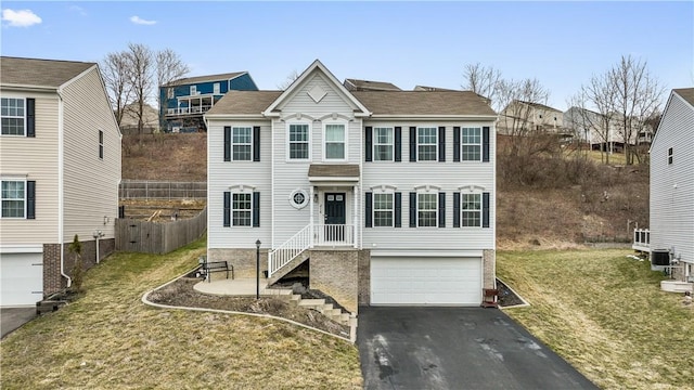 view of front of house featuring a garage, driveway, a front lawn, and fence