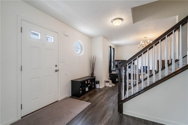 entryway featuring stairs, dark wood-type flooring, baseboards, and a notable chandelier