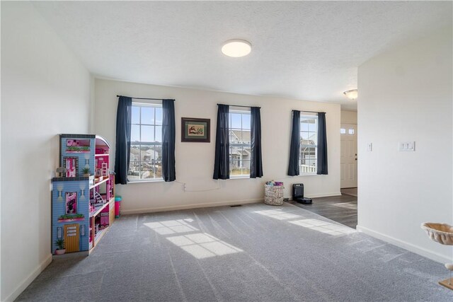 spare room featuring a textured ceiling, carpet flooring, and baseboards