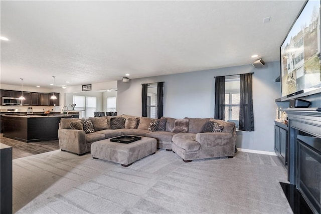 living room featuring recessed lighting, a glass covered fireplace, and baseboards