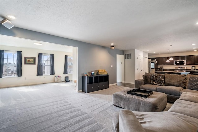 living area with light carpet, baseboards, visible vents, a textured ceiling, and recessed lighting