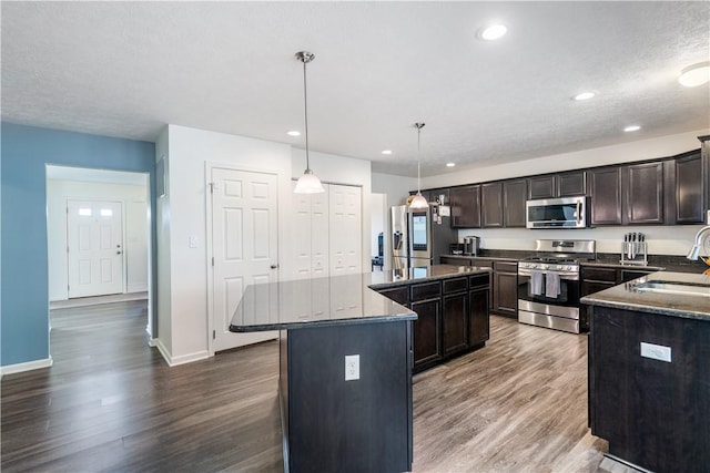 kitchen with dark brown cabinetry, dark wood-style floors, a center island, stainless steel appliances, and a sink