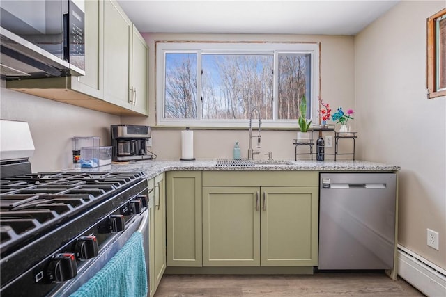 kitchen with light wood-style flooring, appliances with stainless steel finishes, baseboard heating, green cabinets, and a sink