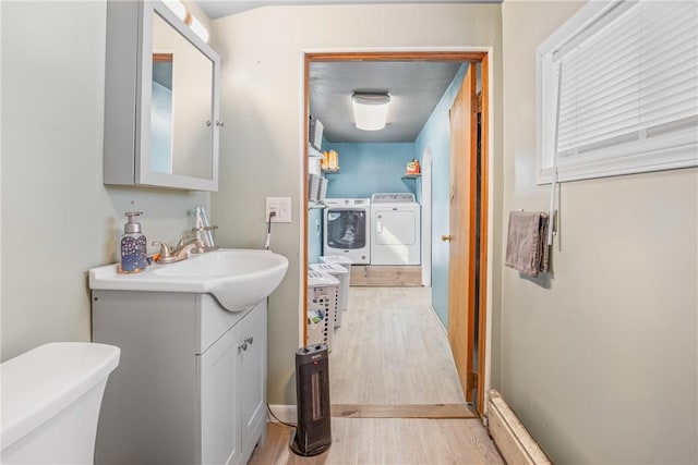 half bath with toilet, washing machine and dryer, wood finished floors, and vanity