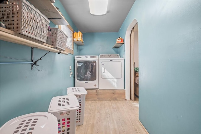 laundry area with arched walkways, laundry area, washer and clothes dryer, and wood finished floors