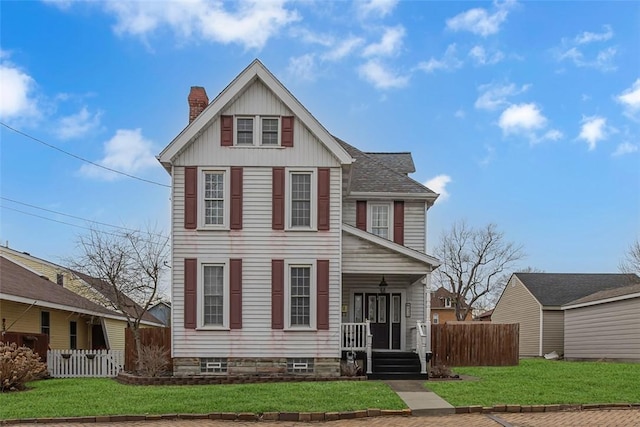 view of front of house featuring a chimney, fence, board and batten siding, and a front yard