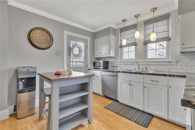 kitchen featuring stainless steel appliances, light wood-style floors, a wealth of natural light, and a sink