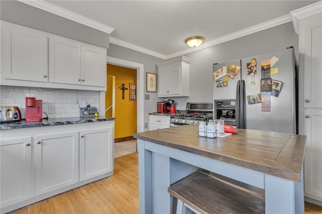 kitchen featuring light wood-style flooring, white cabinets, ornamental molding, appliances with stainless steel finishes, and tasteful backsplash