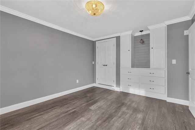 unfurnished bedroom featuring dark wood-style floors, a closet, baseboards, and crown molding