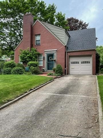 view of front of house featuring driveway, a chimney, an attached garage, a front yard, and brick siding