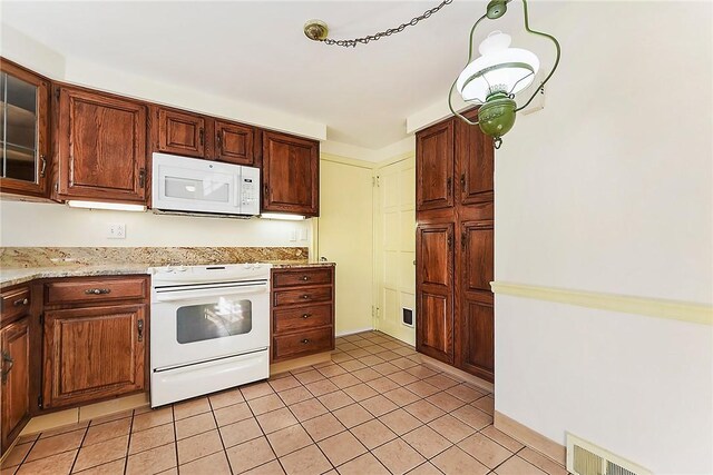 kitchen featuring light stone counters, light tile patterned floors, visible vents, glass insert cabinets, and white appliances