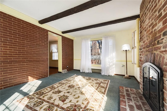 interior space with brick wall, a fireplace, beam ceiling, and a healthy amount of sunlight