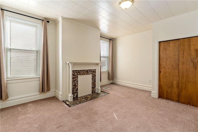 unfurnished living room with baseboards, a fireplace, ornamental molding, and carpet flooring