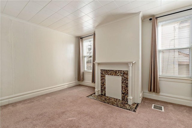 unfurnished living room featuring a tile fireplace, visible vents, carpet flooring, and ornamental molding