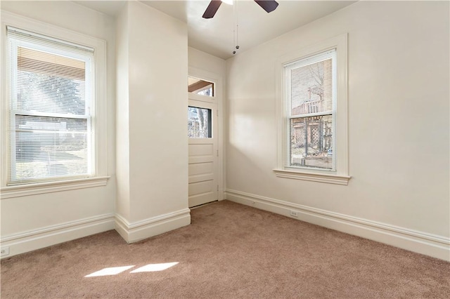 empty room with light carpet, a ceiling fan, and baseboards