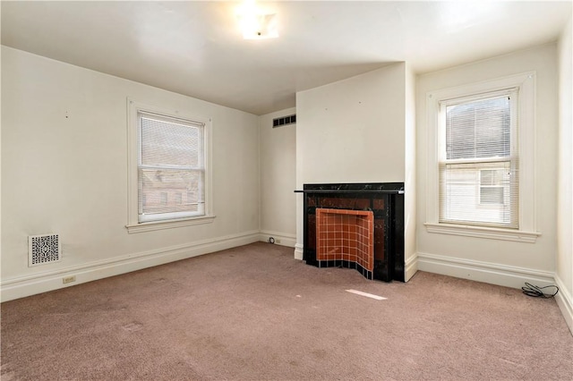 unfurnished living room featuring baseboards, a healthy amount of sunlight, a fireplace, and carpet flooring