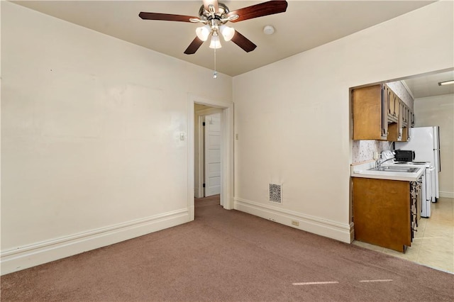 interior space featuring ceiling fan, light carpet, light countertops, backsplash, and brown cabinetry